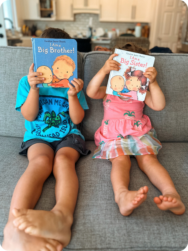 toddlers holding an I am a Big Brother and I am a big Sister book 