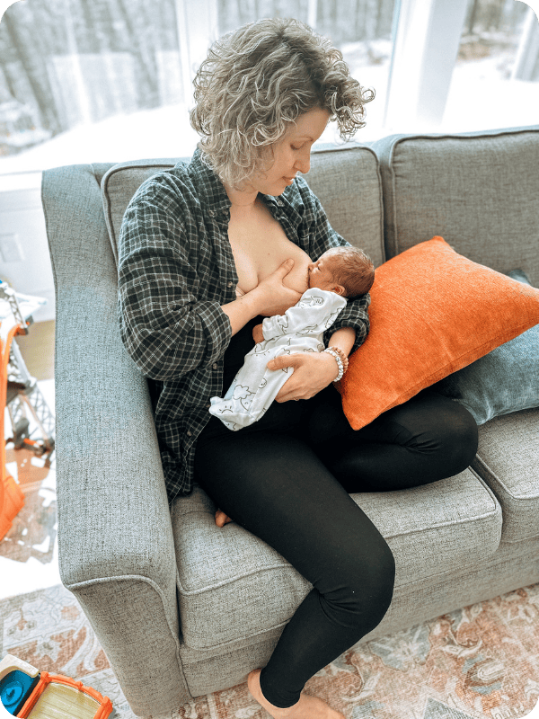 Mom breastfeeds newborn baby on the couch