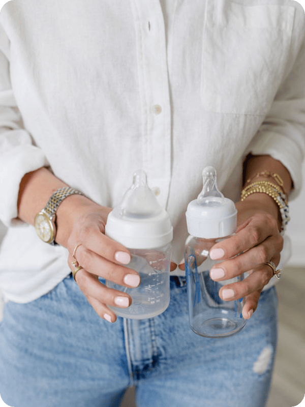 Woman holds two empty baby bottles toward the camera
