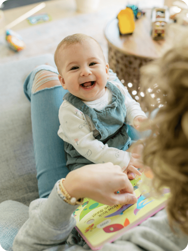 Infant smiles at the camera while sitting in mom's lap