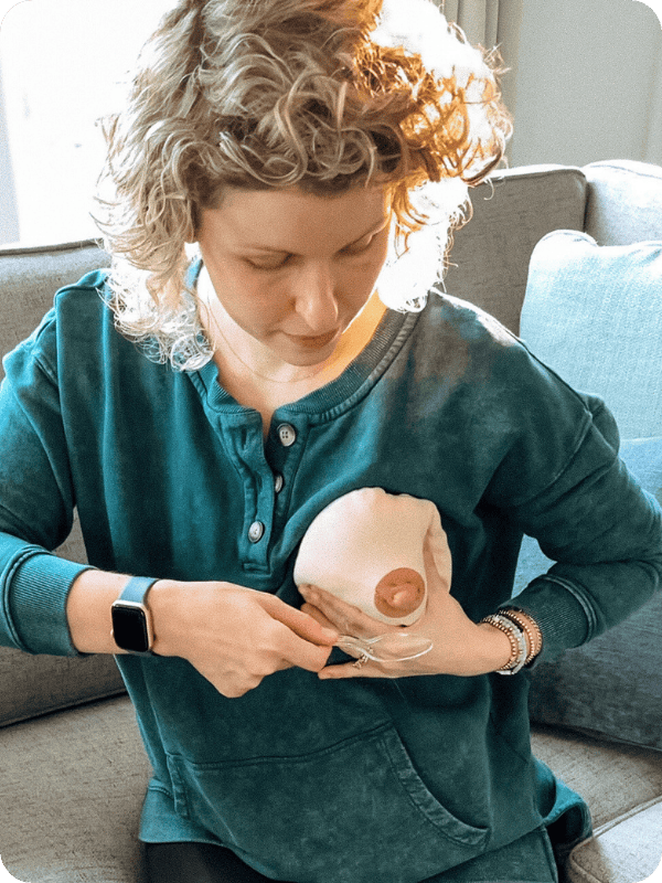 Woman practices collecting colostrum using the spoon method on a fake breast.