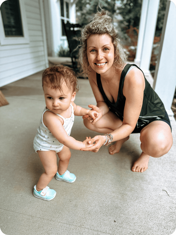 Infant holds mom's hands as she stands up
