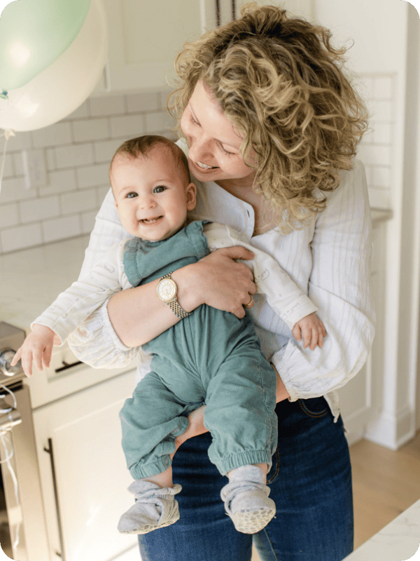 Mom holds her baby, who is smiling at the camera