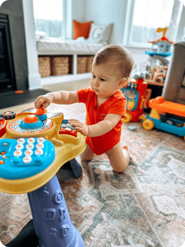 Infant kneels to play at a light up toy