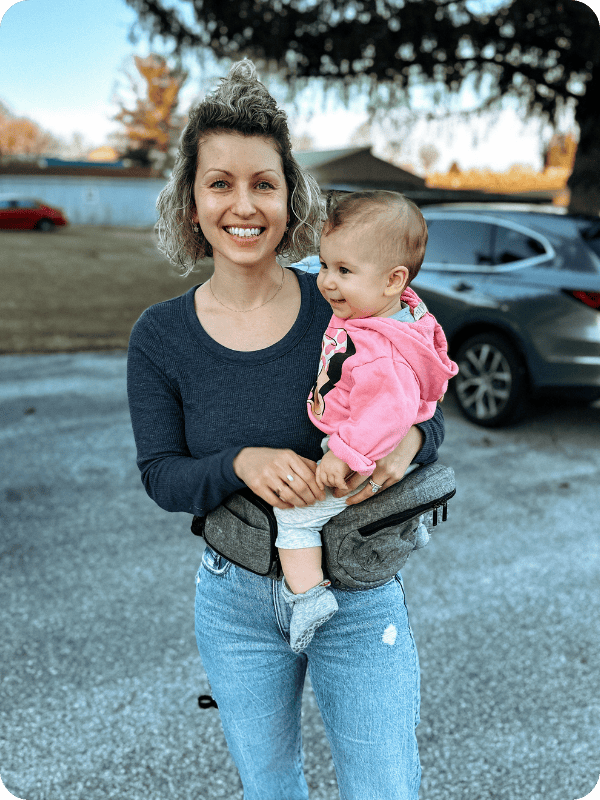 mom using Tushbaby hip carrier to carry baby
