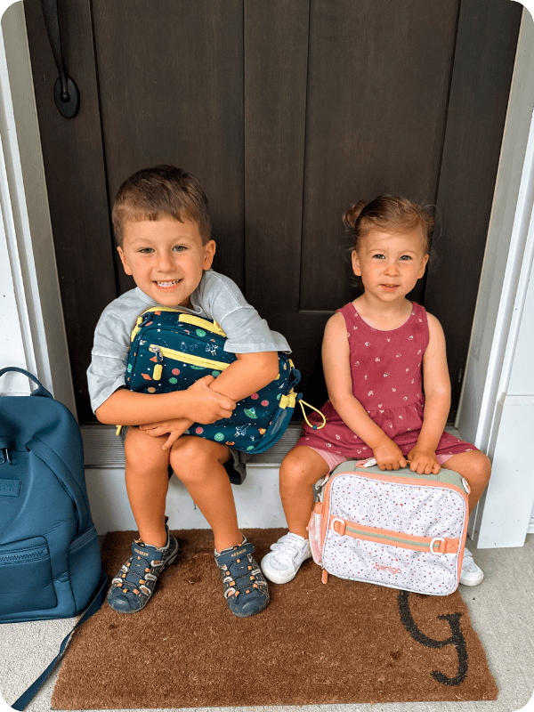 toddlers holding bento lunch boxes before school
