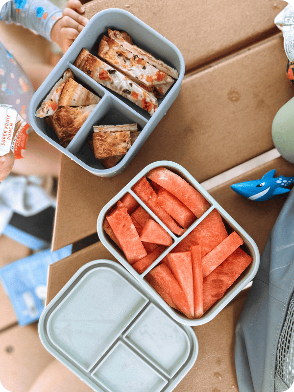 silicone bento boxes holding watermelon and sliced pizza