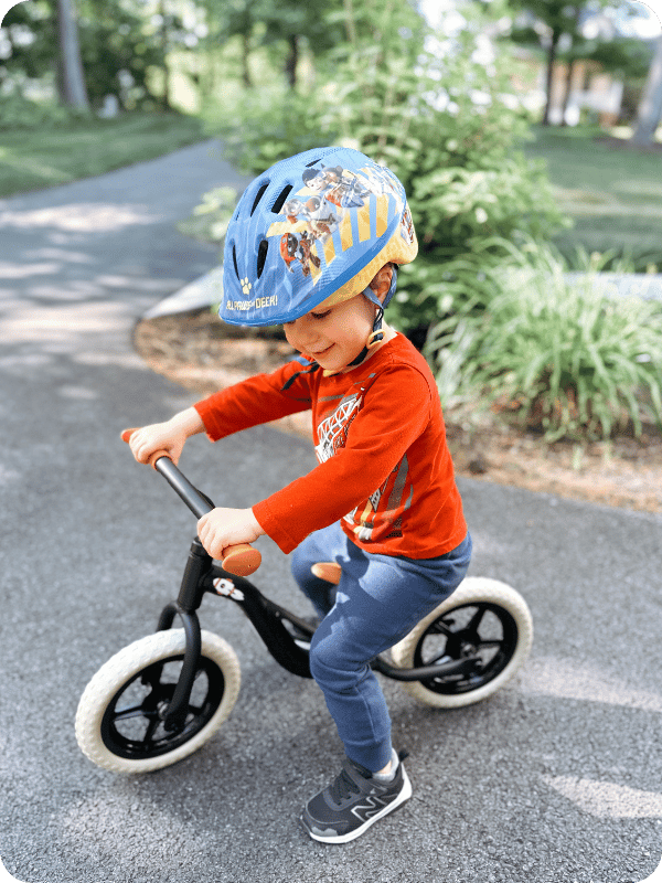 toddler boy riding chillafish balance bike on the driveway
