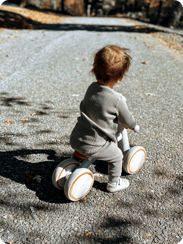 toddler riding a baby balance bike on the gravel