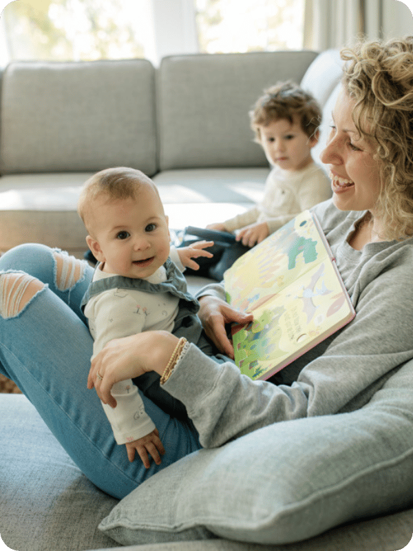 Infant sits on mom's lap facing mom while they look at a book together