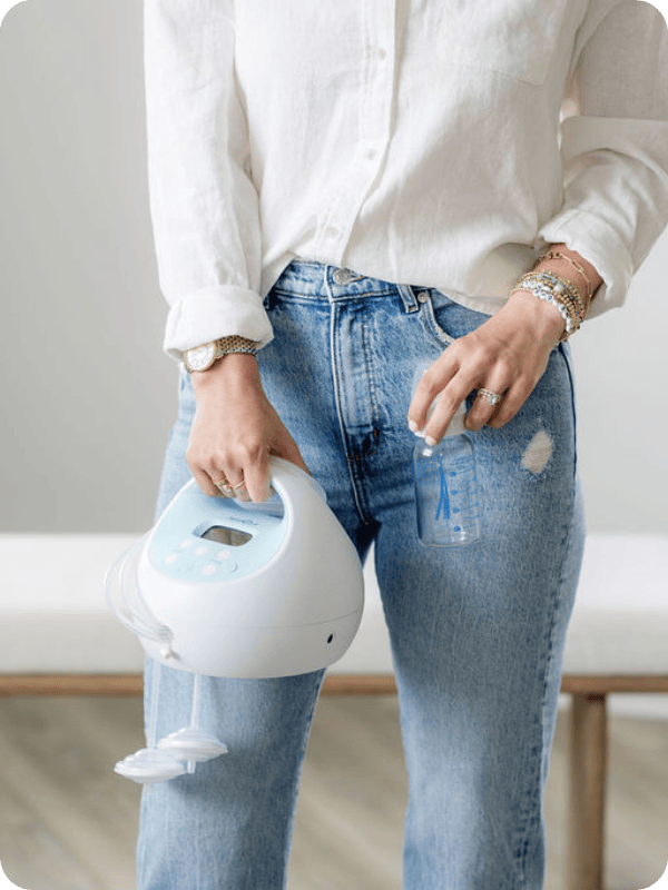 Mom holds a breast pump and a glass bottle.
