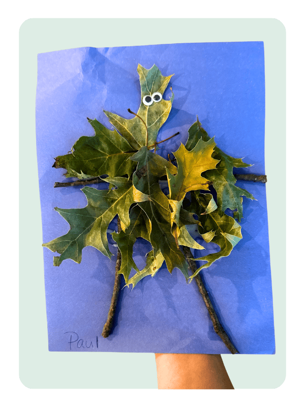 A silly leaf person craft using construction paper for the background and glued leaves and sticks to form the leaf person. Googly eyes complete the craft!