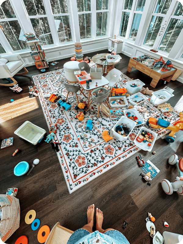 A messy playroom with toys and bins scattered on the floor.