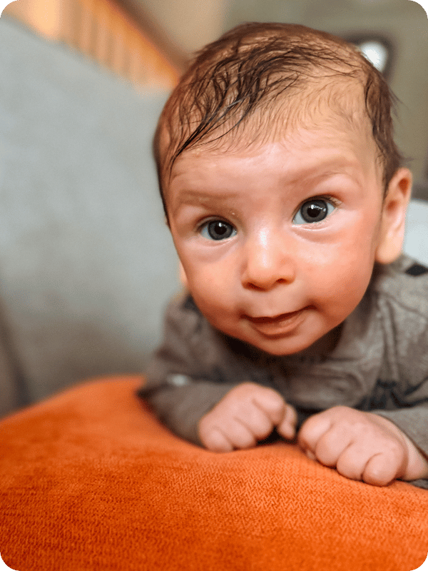 Infant practices propped tummy time with a pillow.
