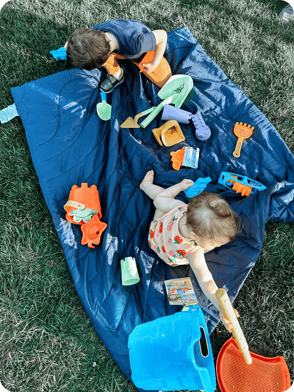 children playing with toys outside on a blanket