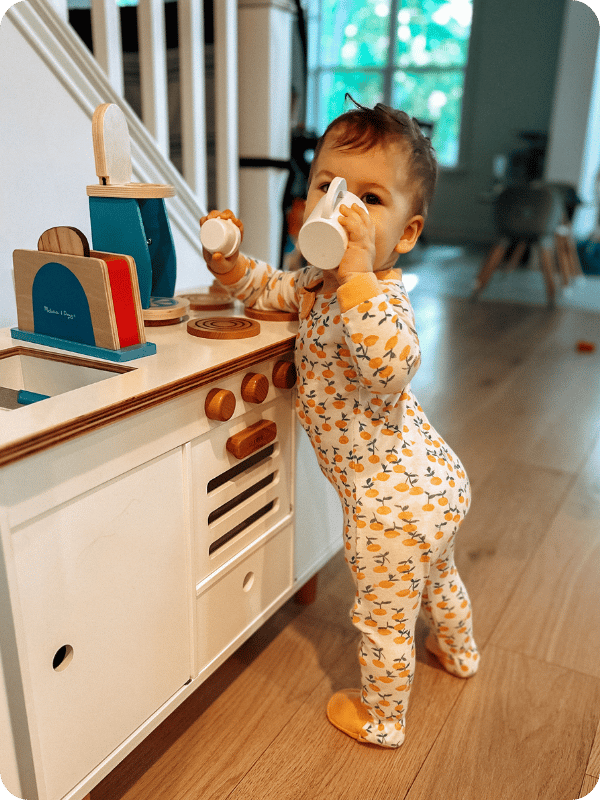 toddler playing at children's play kitchen