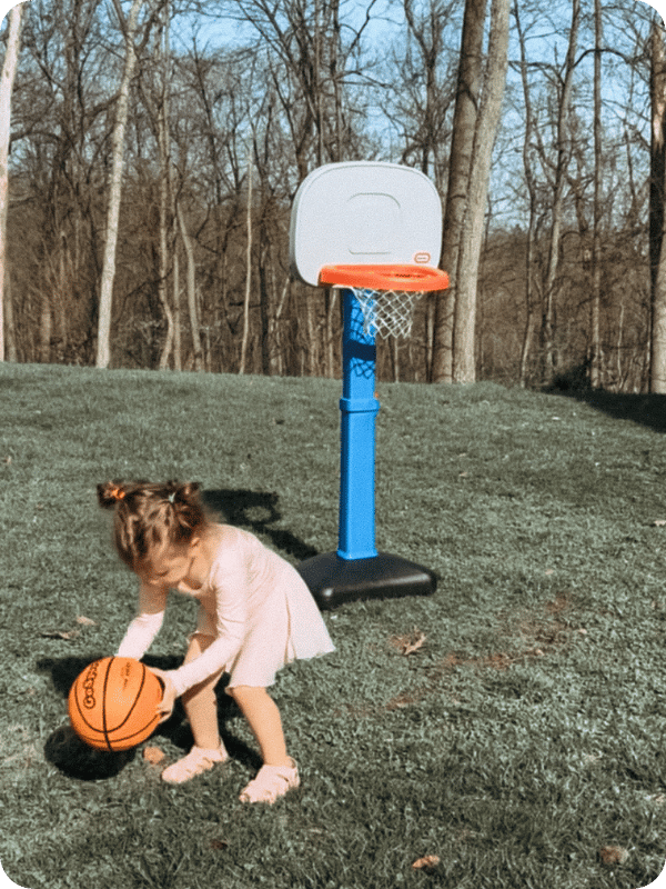 toddler girl playing with a basketball hoop