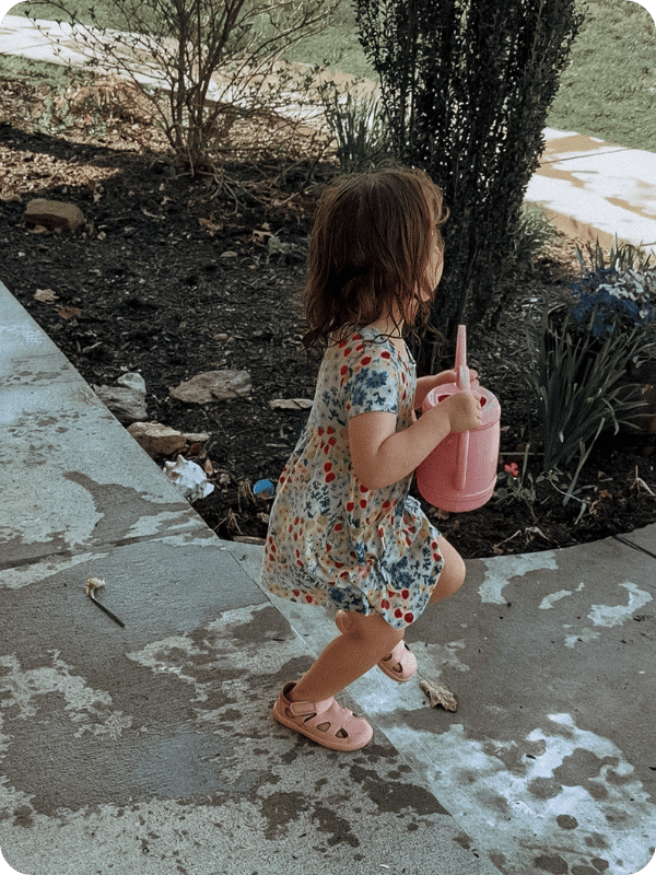 toddler watering plants with watering can