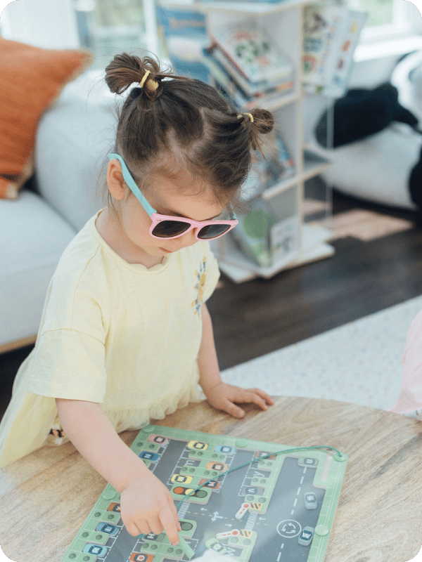 Toddler girl wearing sunglasses plays with a magnetic puzzle