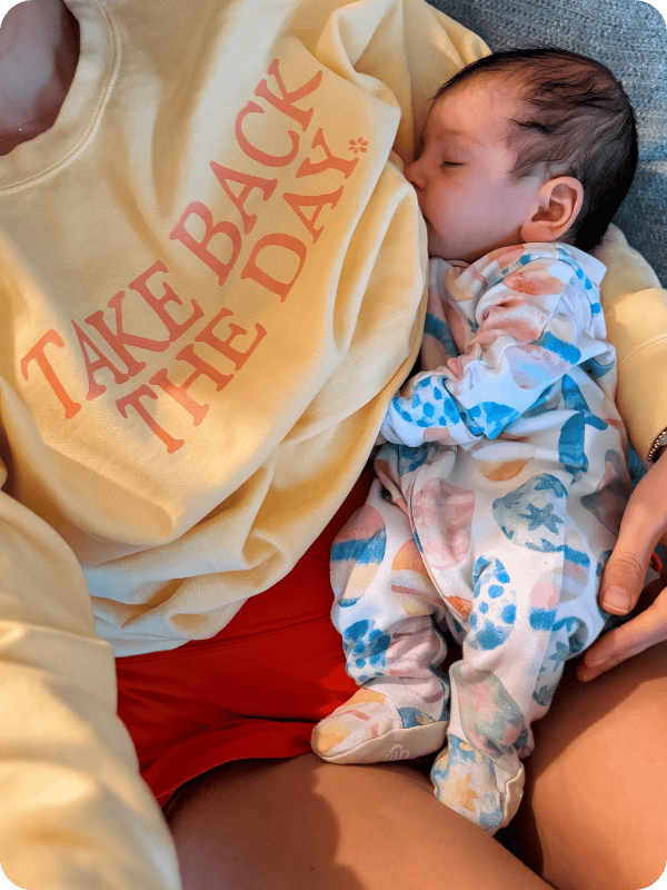 Mom and newborn snuggle on the couch. Mom is wearing a shirt that says "Take back the day."