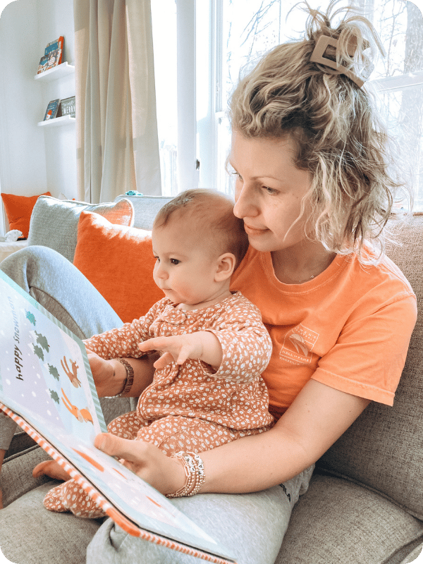 Infant sits in mom's lap as they look at a book together.