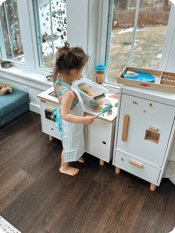 toddler playing with lalo play kitchen as part of pretend play toy post