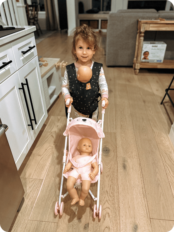 toddler girl playing with baby dolls, pushing them in a stroller