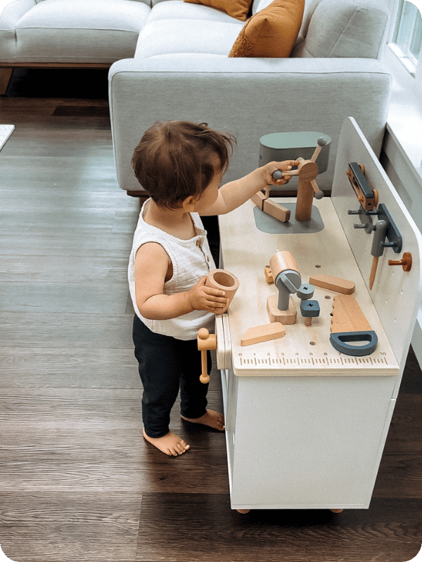 toddler playing with Lalo's kids' workbench in a post about pretend play toys 