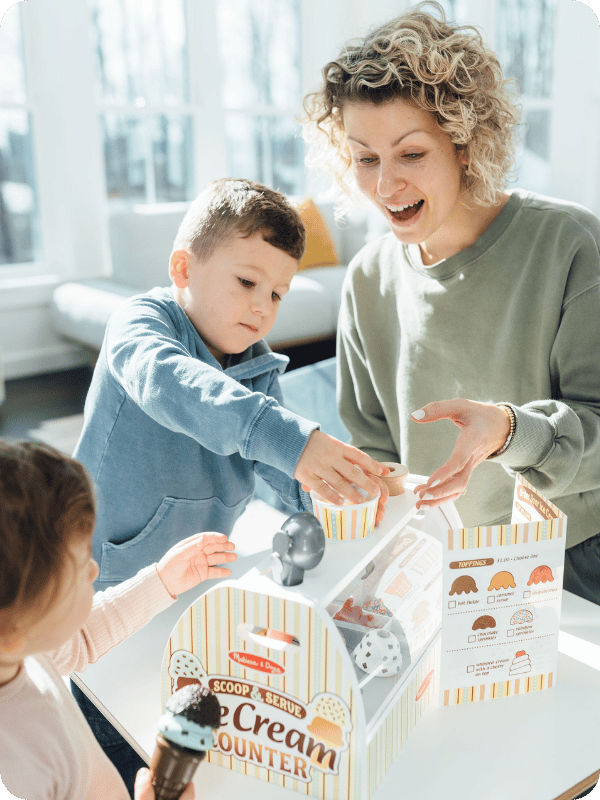 toddlers and their mom playing pretend with an ice cream play food set