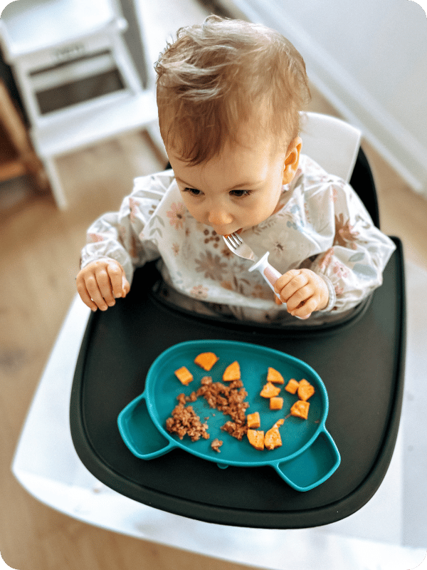 young toddler eating with Bumkins smock bib on