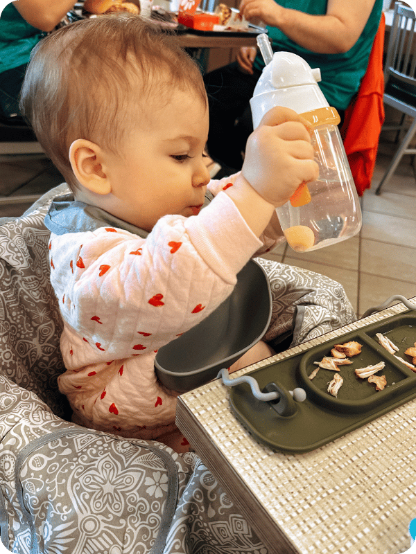 baby wearing Oxo tot roll up bib eating out at a restaurant 