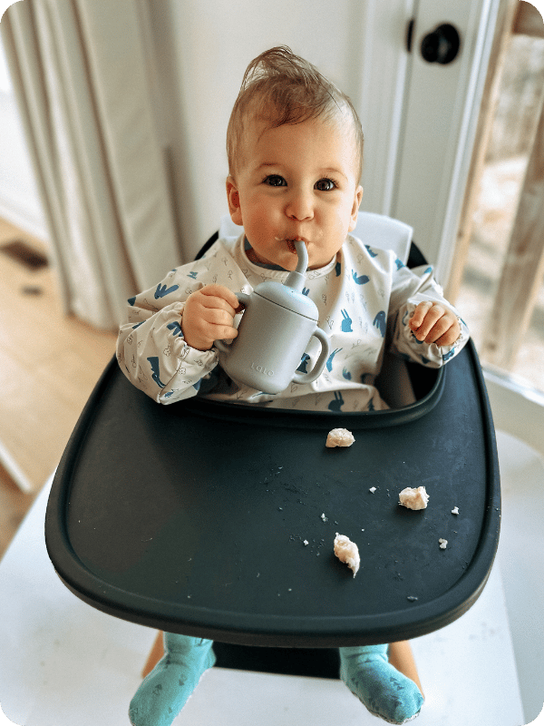 infant wearing Lalo smock bib in the high chair