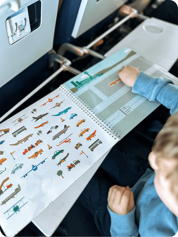 toddler working on sticker book on an airplane 