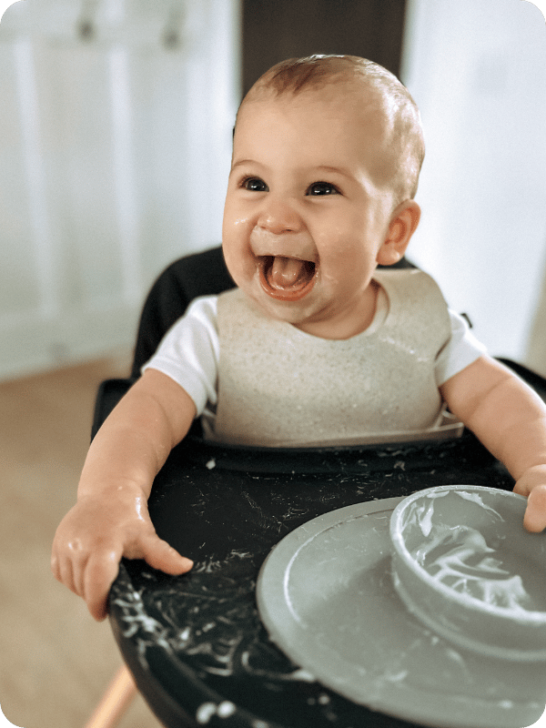 Baby smiles in her high chair after eating yogurt.