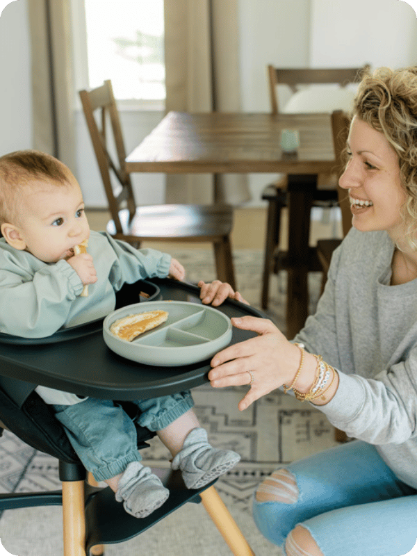 Mom serves baby a meal in the high chair