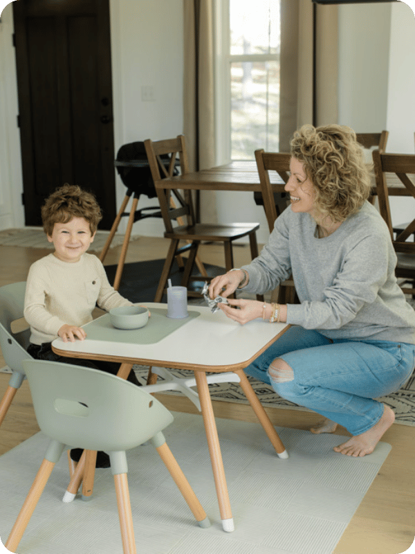 Mom serves toddler a meal at a toddler table
