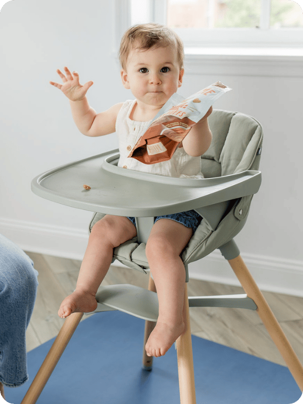 Toddler eats a snack in the high chair