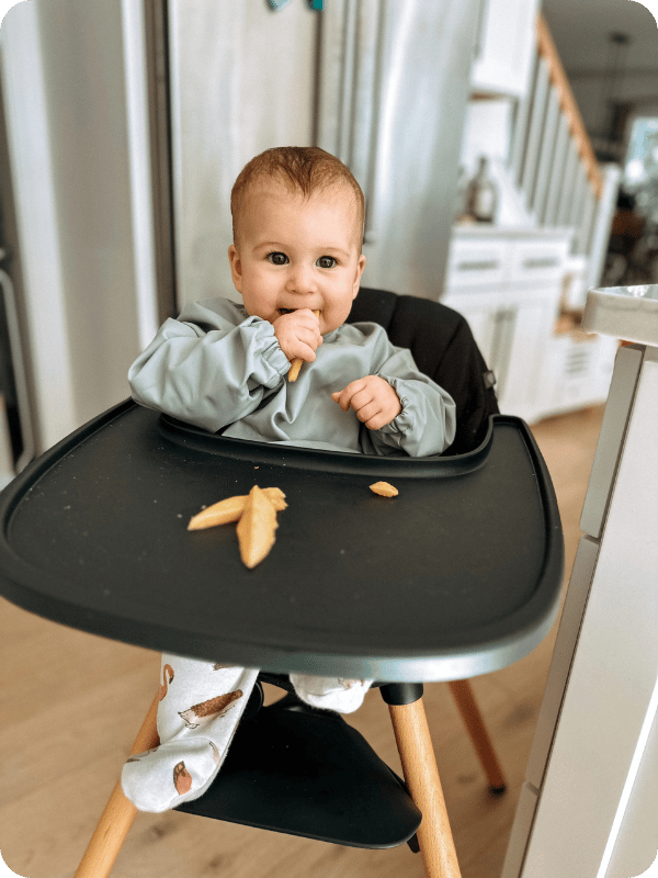 Baby self-feeds in her high chair