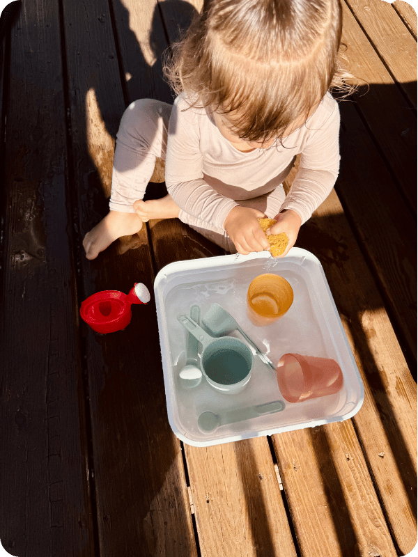 Toddler has fun with sensory play on the deck.