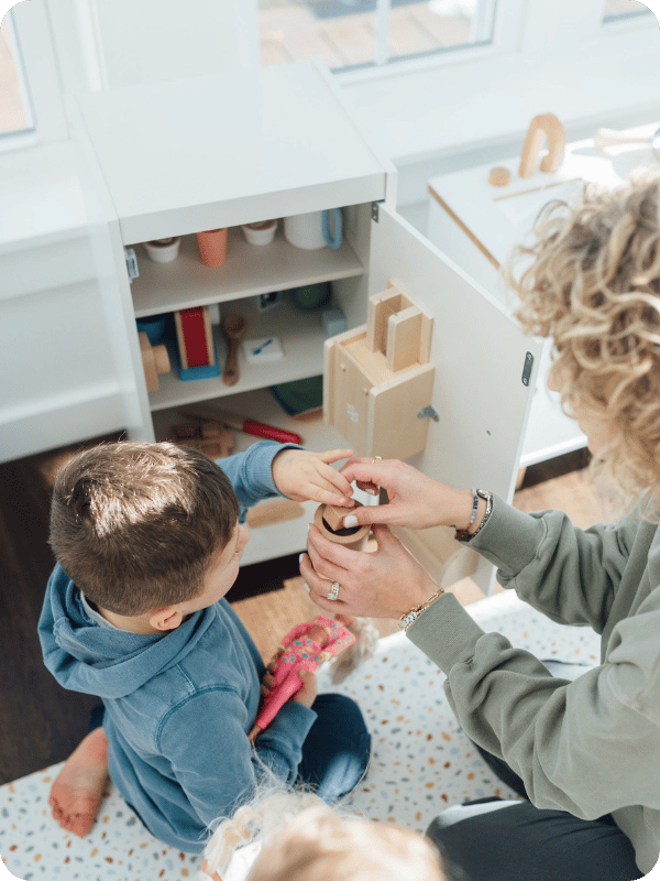 toddler and mom playing with play food in the play kitchen