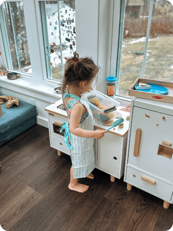 toddler playing at play kitchen