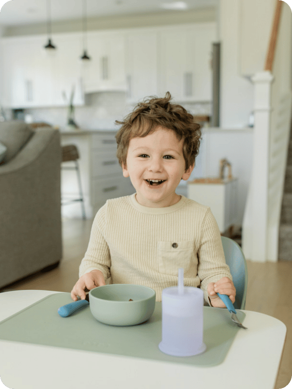 Toddler sits at his toddler table to eat a meal.