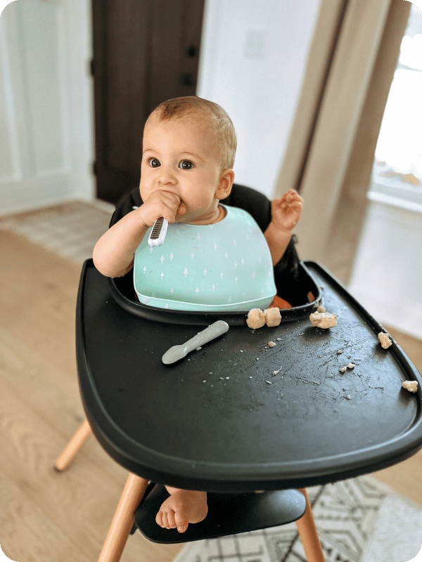 Baby uses the foot rest on her high chair when eating a meal.