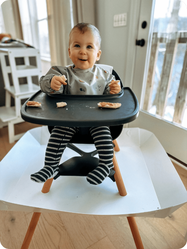 Baby sits 90-90-90 in her high chair during a meal.