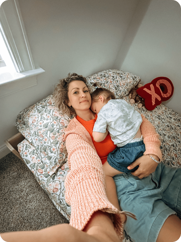 Mom supporting her toddler to sleep in a floor bed.