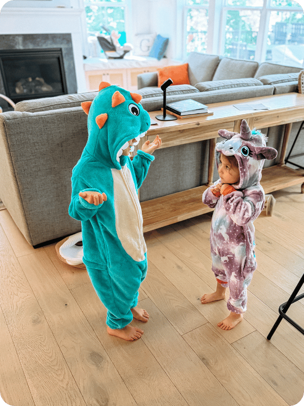 two toddlers playing dress up in dinosaur and unicorn costumes