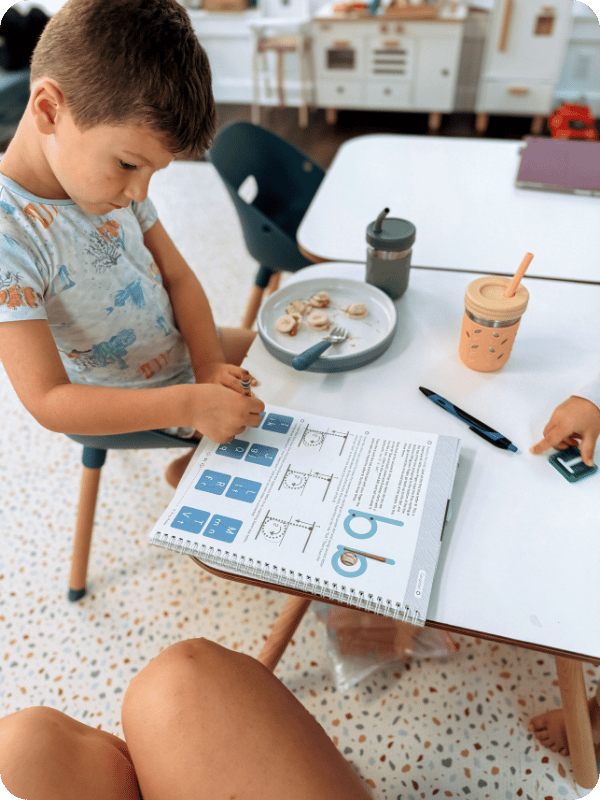 Preschooler works on letter recognition and tracing while eating a snack.