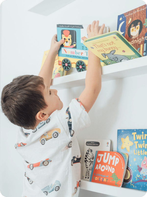 Preschooler grabs a book from a bookshelf.