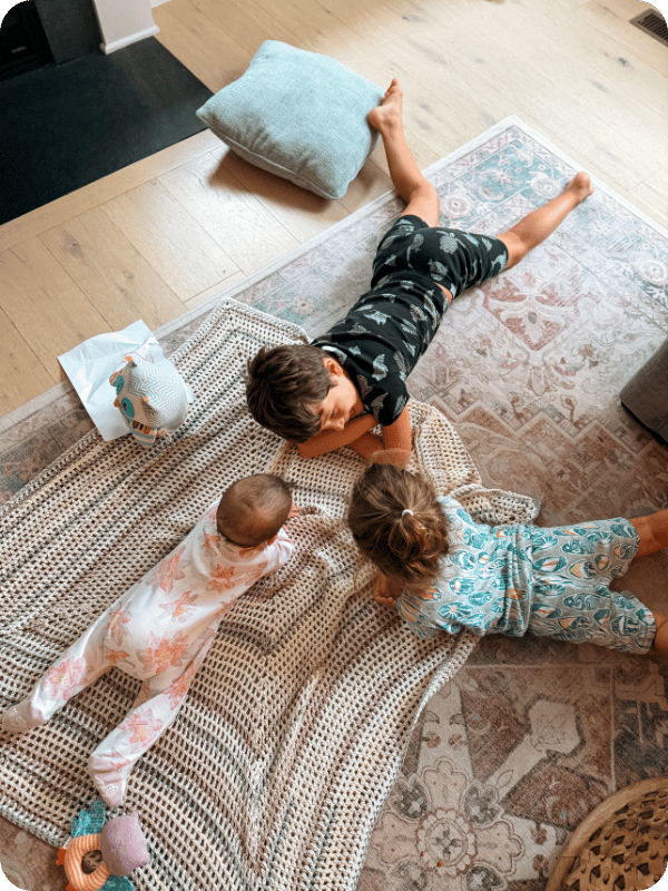 Baby and two big siblings lay on the floor together to "talk"