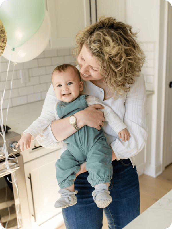 Mom and baby smile in the kitchen.